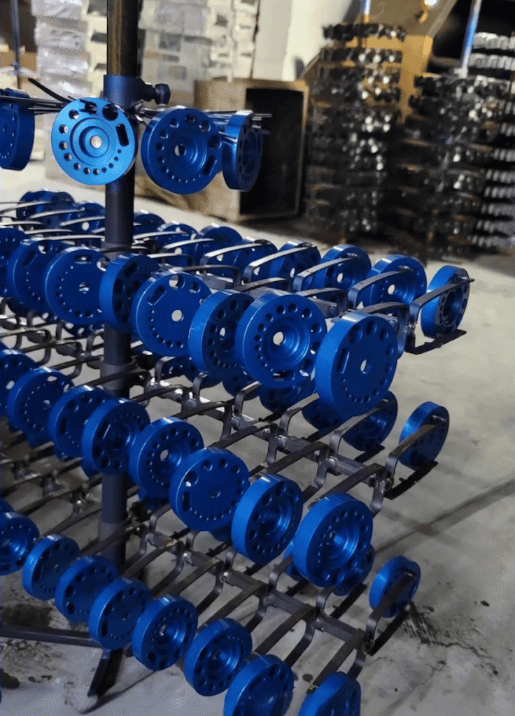 Blue CNC machined parts displayed on a rack in a manufacturing facility.