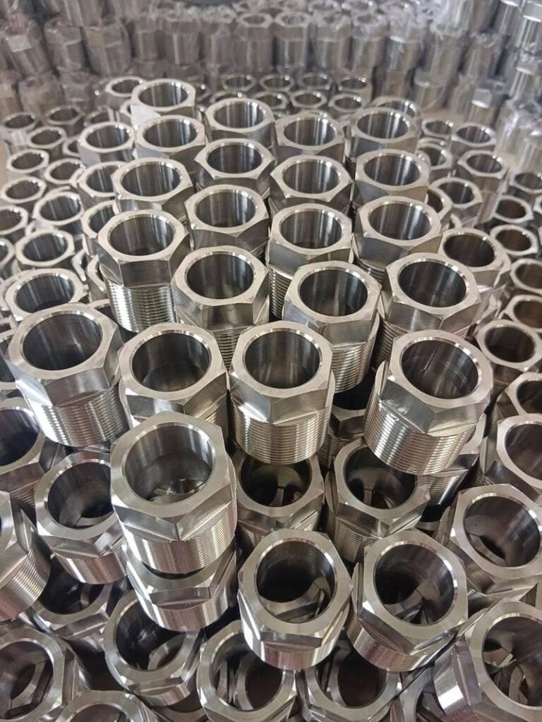 Aluminum CNC machined hexagonal nuts arranged in a pile for manufacturing.