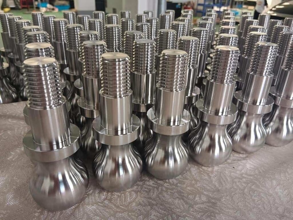 Precision machined metal components with threaded tops arranged in rows.