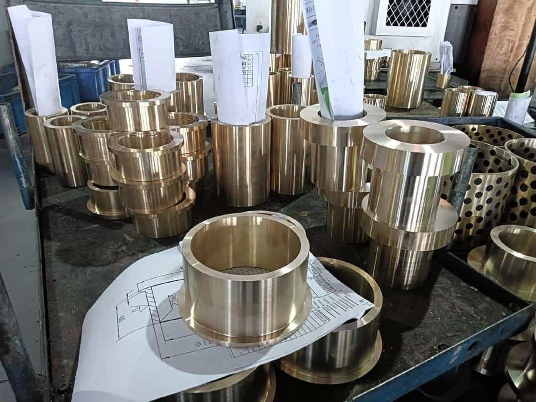High-precision CNC machined brass components with technical drawings on a workbench.