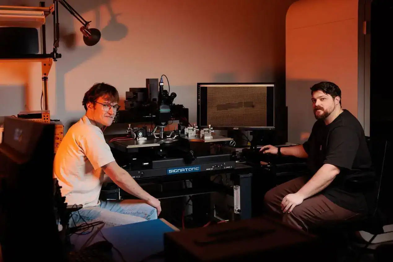 A technician and engineer working on CNC machinery in a workshop setting.