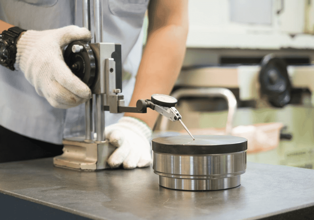 Precision CNC machining process with a dial indicator and metal parts.