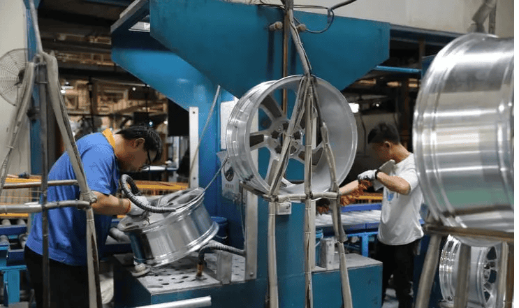Workers are performing post-processing polishing on car rims