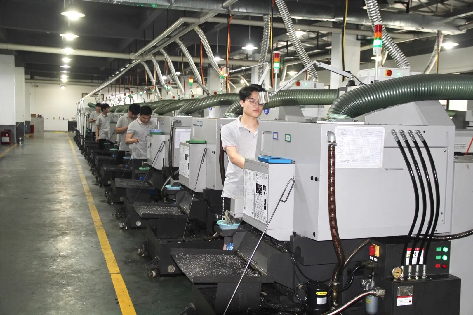 Operators working along a Swiss CNC machining production line