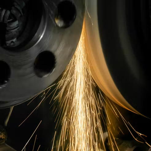 An abrasive wheel removing material from a metal component