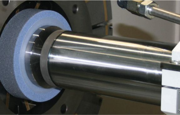 A grinding wheel finishing the outside of a cylindrical workpiece