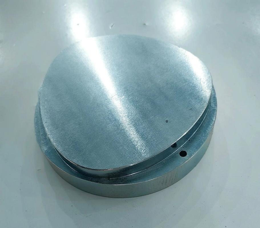 Round metal component with a broad machined flat face