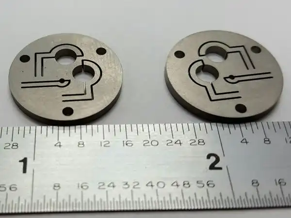 Two small round metal parts with fine internal wire cut channels