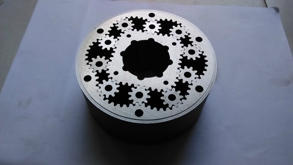 Round metal component with multiple intricate gear-shaped openings